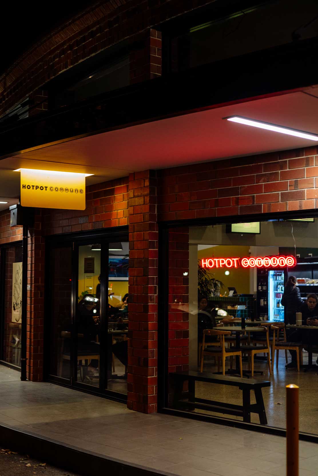Proud franchise owner standing inside a lively hotpot restaurant.